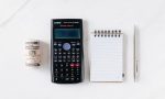 composition of calculator with paper money and notebook with pen